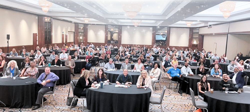 Members of the National Center for Community-Based Child Welfare gathered at the annual symposium around round tables with black tablecloths. 