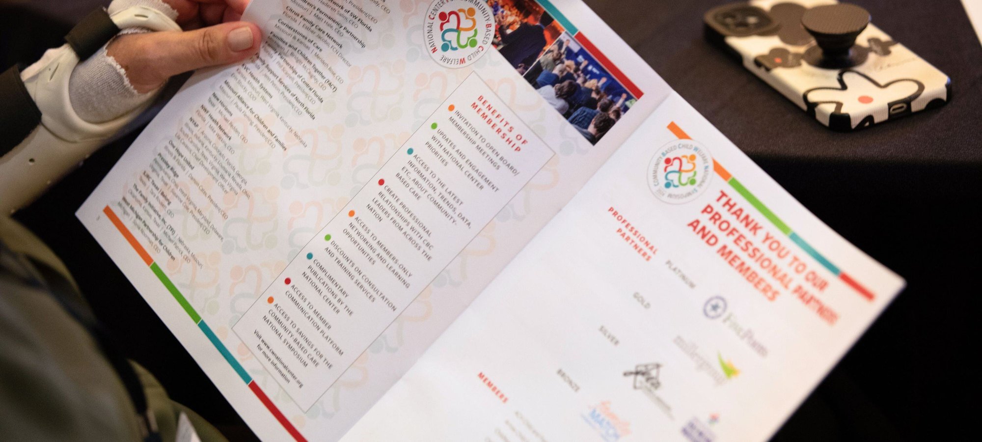 A closeup of the National Center for Community-Based Child Welfare’s 2024 Symposium booklet showing all the logos of its partners, members, and sponsors. 