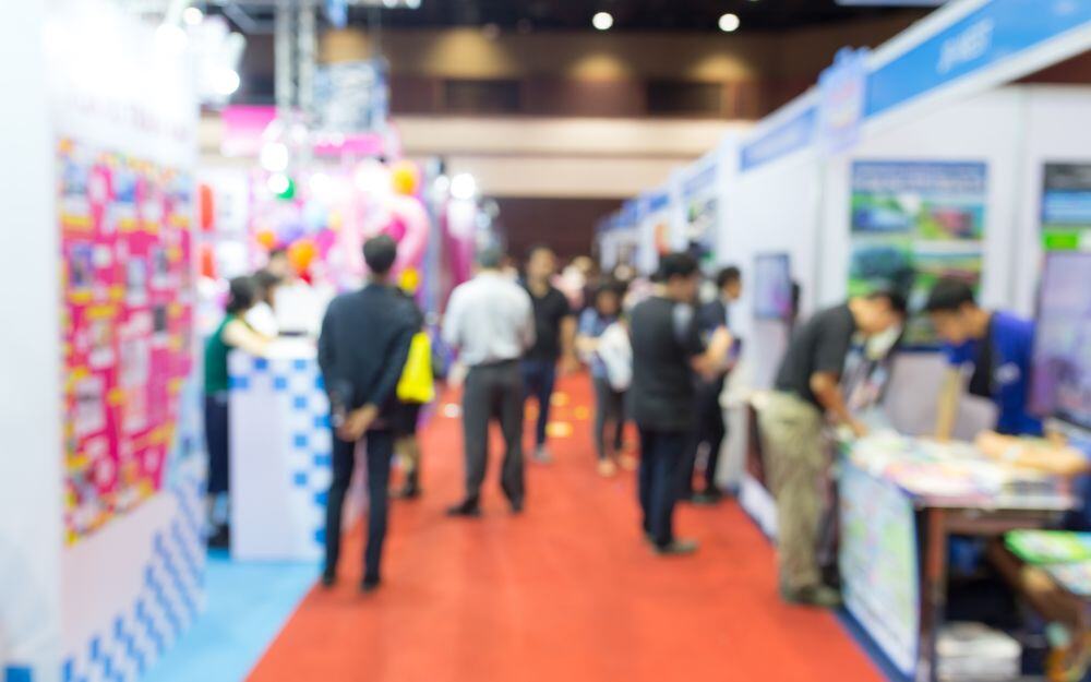 Professionals walking among booths provided by sponsors and partners at the annual symposium of the National Center for Community-Based Child Welfare. 