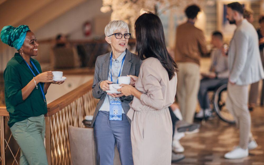 Three professionals networking while taking a coffee break during the annual symposium of the National Center for Community-Based Child Welfare. 